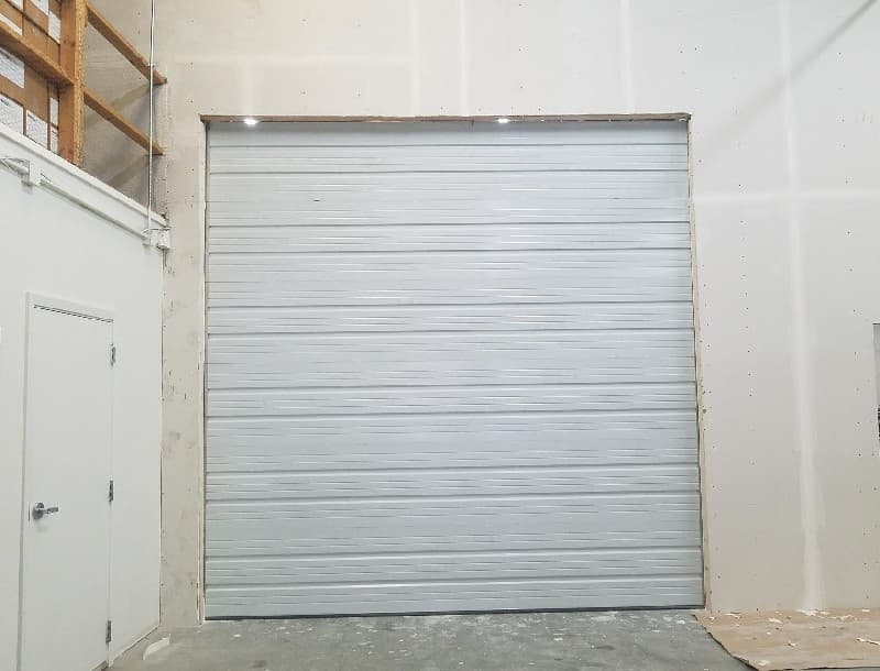 Large white sectional overhead door installed in a commercial unit