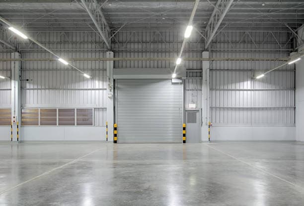 Rolling steel door at the end of a bright warehouse interior with a polished concrete floor